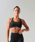 Woman wearing a black sports bra and leggings on a gray background