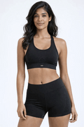 Woman wearing a black sports bra and shorts on a white background