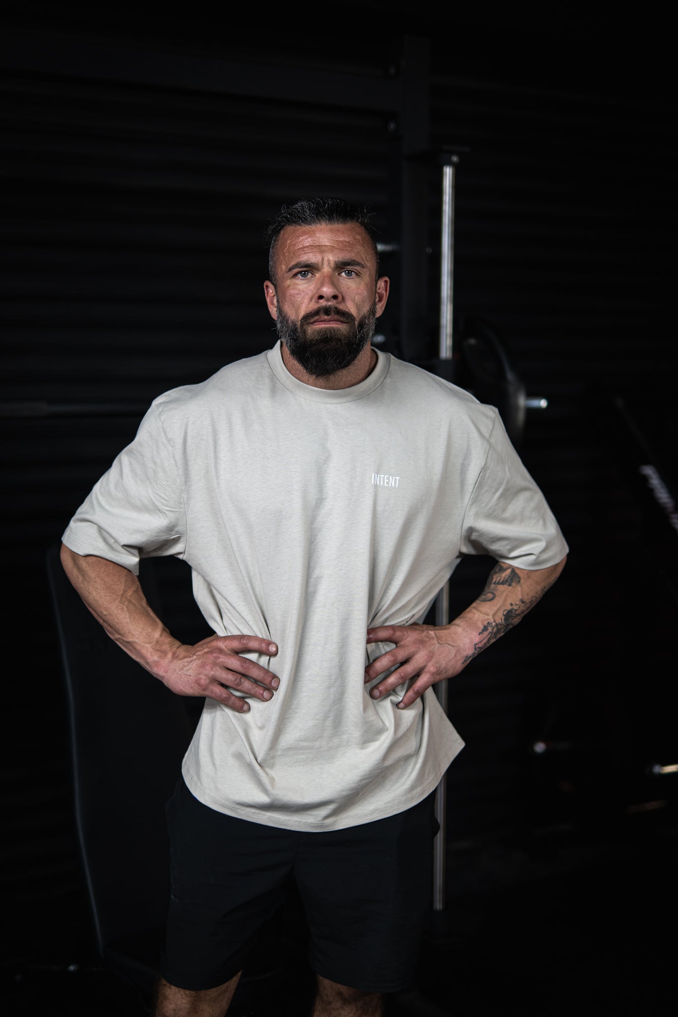 Man wearing a white t-shirt and black shorts against a dark background