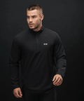 Man wearing a black long-sleeve shirt with a brand logo on a dark background