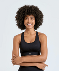 Woman wearing a black sports bra with a visible brand logo on a light gray background