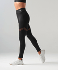 Person wearing black leggings with mesh panels on a gray background