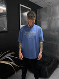 Man wearing a blue t-shirt with 'Invent Lift' text in a room with black walls and a plant.