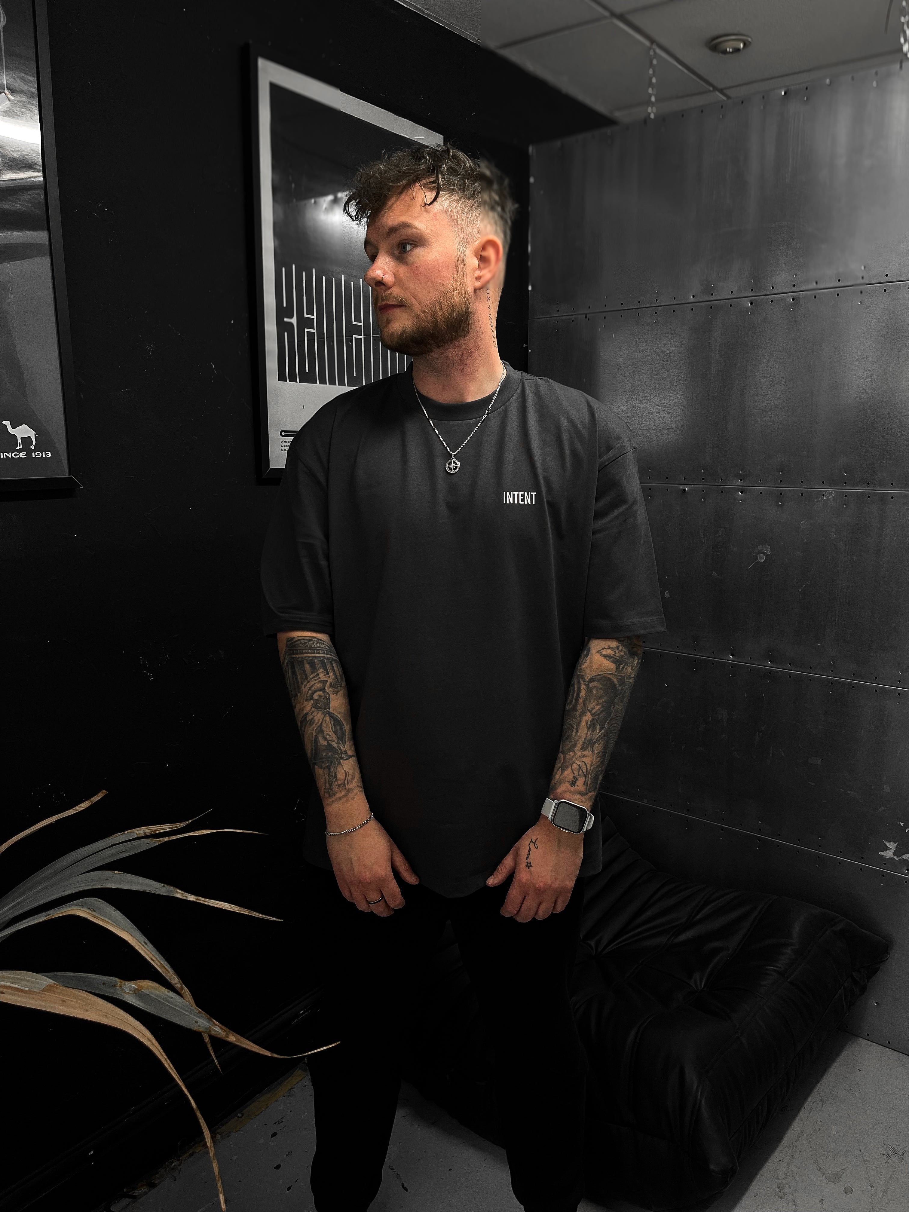 Man wearing a black t-shirt with text in a dark room